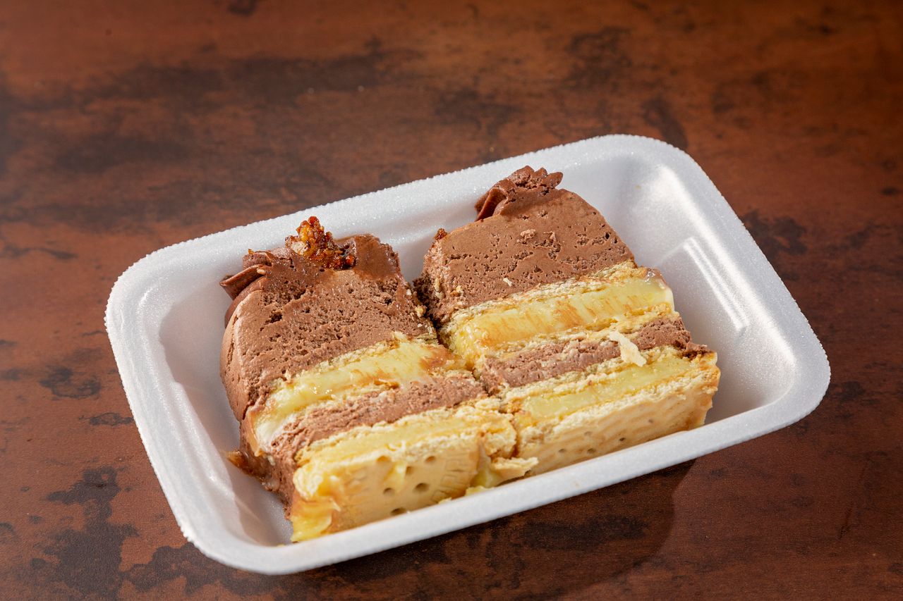 Delicious close-up of a chocolate and vanilla layer cake served in a Styrofoam tray.