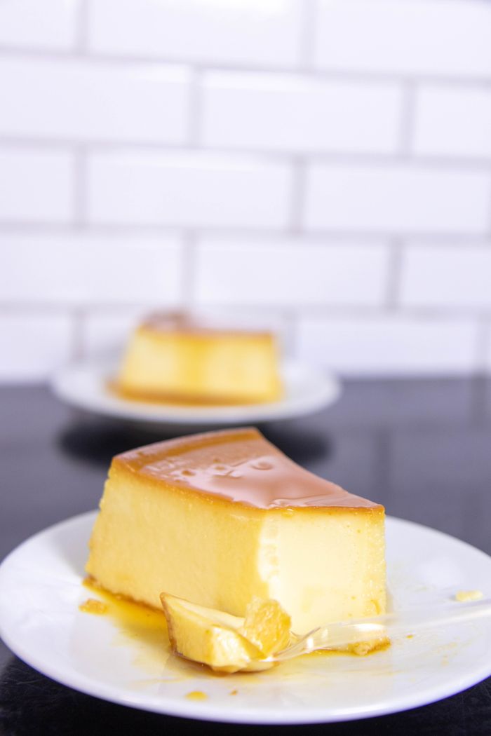 Mastering the First Impression: Your intriguing post title goes here A mouth-watering slice of caramel-topped flan on a white plate with a brick wall background.