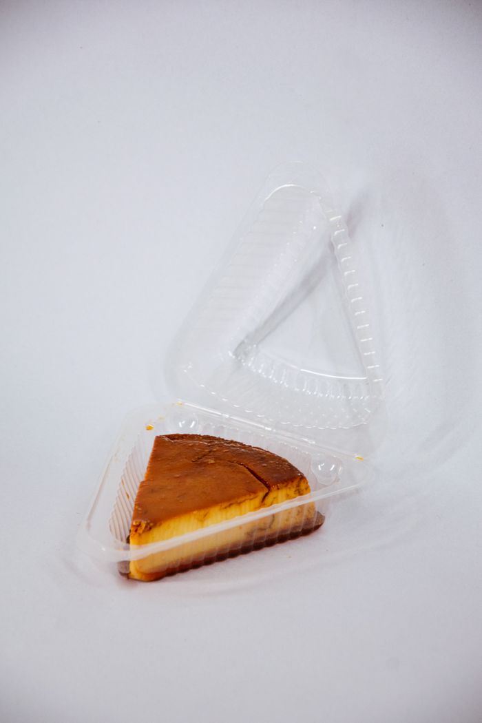 Crafting Captivating Headlines: Your awesome post title goes here Delicious cheesecake slice in a clear plastic takeout container, isolated on white background.